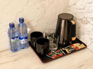 a tray with cups and bottles of water on a counter at Best One Hotel in Jizzax