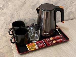 a tray with a coffee pot and cups and drinks at Best One Hotel in Jizzax +16 photos