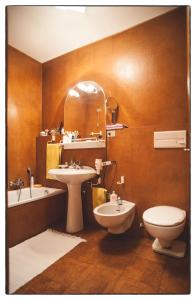 een badkamer met een wastafel, een toilet en een spiegel bij Casa Mizzau in Camporosso in Valcanale