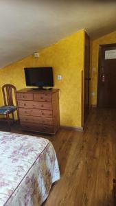 a bedroom with a dresser with a flat screen tv at Hostería Carmen in Santillana del Mar +30 photos