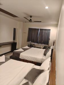 a bedroom with two beds and a ceiling fan at Hotel Ambika Imperio in Vijayawāda
