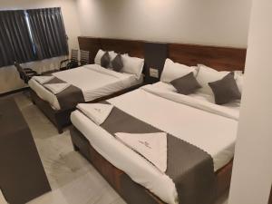 two beds in a hotel room withskirts at Hotel Ambika Imperio in Vijayawāda