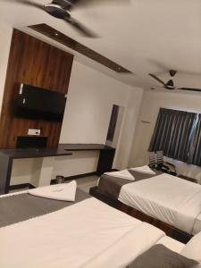 a hotel room with two beds and a tv at Hotel Ambika Imperio in Vijayawāda