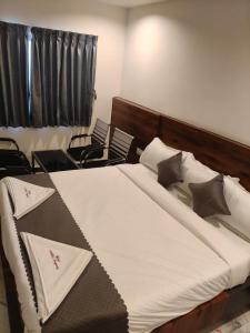 a bedroom with a large bed with chairs in it at Hotel Ambika Imperio in Vijayawāda