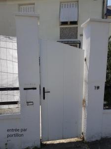 two white doors in front of a white house at Chambre Simple avec parking gratuit in Bourges
