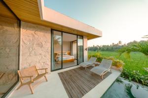 a house with a deck with two chairs and a bed at Casa Ariana in Ubud