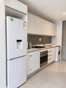 a white kitchen with a refrigerator and a dishwasher at Ocean Dunes Bachelor Apartments in Umhlanga