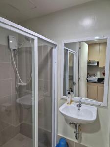 a bathroom with a sink and a shower with a mirror at CozyNest Rentals at Brenthill Condominium in Baguio
