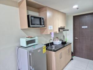 a small kitchen with a refrigerator and a microwave at CozyNest Rentals at Brenthill Condominium in Baguio