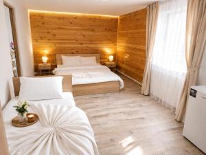 two beds in a room with wooden walls at Casa AIDA in Peşteana