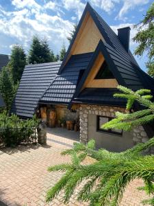 a house with a black roof and a brick driveway at Orla Przystań in Gliczarów Górny