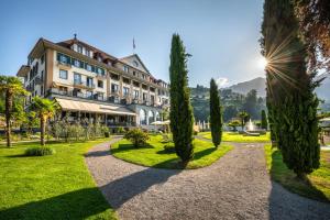 a hotel with trees in front of a building at Parkhotel Gunten – Beach & Spa in Gunten