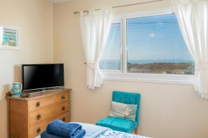 a bedroom with a bed and a television and a chair at Ty Peggie in Haverfordwest