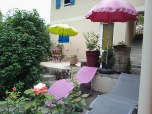 two purple chairs and an umbrella on a patio at le studio de la salamandre in Cadillac