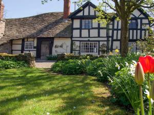 a black and white house with a yard with flowers at The Old Barn in Hereford