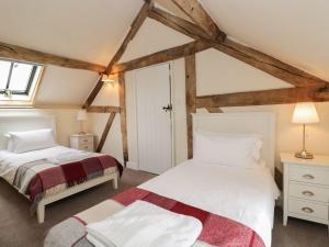 two beds in a room with wooden beams at The Old Barn in Hereford