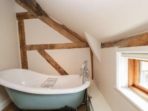 a bath tub in a bathroom with wooden beams at The Old Barn in Hereford