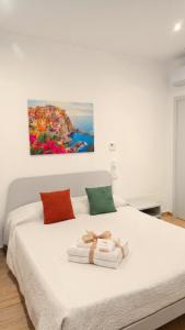 a bedroom with a white bed with a painting on the wall at Real Rooms in La Spezia