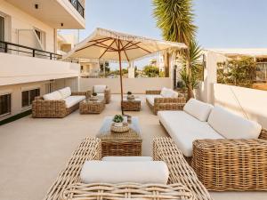 a patio with wicker furniture and an umbrella at AVENA Suites in Kato Gouves