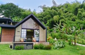een klein huis met een veranda met horren in een tuin bij Macana Eco Hotel in Montenegro
