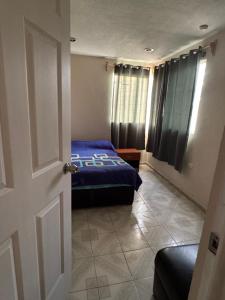 a bedroom with a bed with a blue comforter at Santa Rosalía3- 2 habitaciones in San Felipe Hueyotlipan