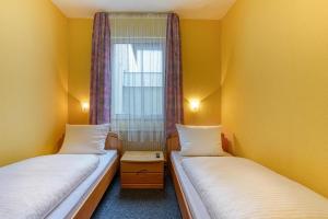 two beds in a small room with a window at Central Station Hotel Dortmund in Dortmund