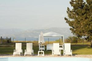 a group of chairs and a table and a white umbrella at Mariposa Apartments in Kavos