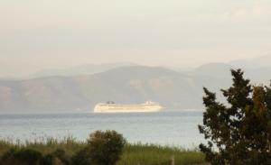 a cruise ship in the water with mountains in the background at Mariposa Apartments in Kavos +16 photos