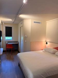 a bedroom with a white bed and a desk and a table at ibis budget Brive La Gaillarde in Brive-la-Gaillarde +35 photos