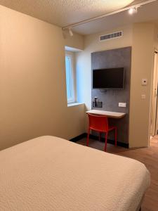 a room with a bed and a table and a tv at ibis budget Brive La Gaillarde in Brive-la-Gaillarde
