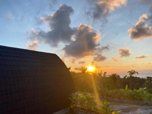 a sunset behind a building with the sun in the sky at The Southeast Penida in Polilit