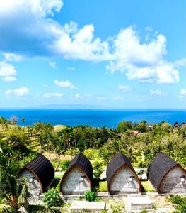 a group of cottages with the ocean in the background at The Southeast Penida in Polilit