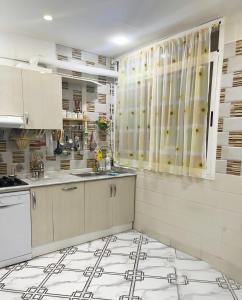 a kitchen with white cabinets and tile floors at Apartment - Jijel in Jijel