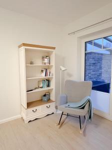 a white room with a chair and a book shelf at Ferienwohnung Knut in Lütjenbornholt