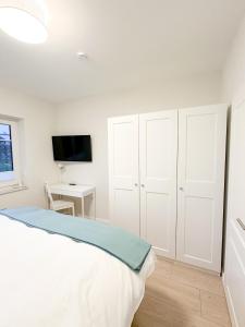 a white bedroom with a bed and a desk at Ferienwohnung Knut in Lütjenbornholt +26 photos