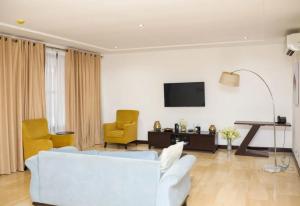 a living room with a white couch and two yellow chairs at Premier Place, Sky Suites in Accra