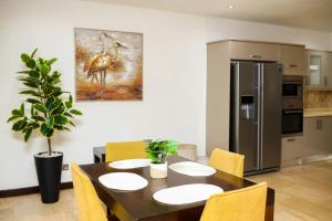 a dining room with a table and a refrigerator at Premier Place, Sky Suites in Accra