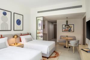 a hotel room with two beds and a table at Bloom Arjaan by Rotana in Abu Dhabi +49 photos