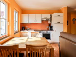 an orange kitchen with a wooden table and chairs at Gerlach in Zingst