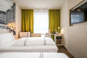 two beds in a hotel room with green curtains at Premier Inn Hamburg City Berliner Tor in Hamburg +22 photos