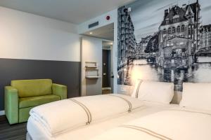 a bedroom with a bed and a green chair at Premier Inn Hamburg City Berliner Tor in Hamburg