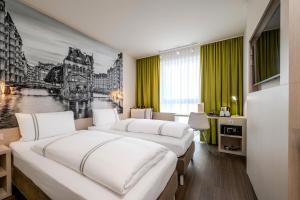 two beds in a hotel room with green curtains at Premier Inn Hamburg City Berliner Tor in Hamburg