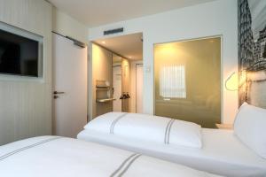 two white beds in a room with a mirror at Premier Inn Hamburg City Berliner Tor in Hamburg