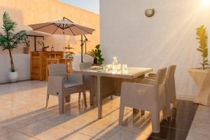 a dining room with a table and chairs and an umbrella at Le Rooftop Apparte - Barbecue, Grande Terrasse in Nabeul