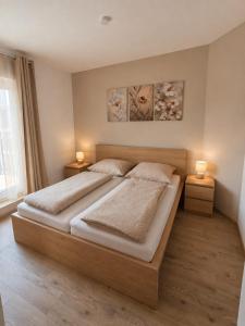 a bedroom with a large bed with two lamps on two tables at MarchfeldStay in Gänserndorf