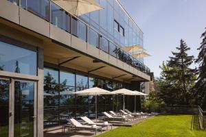 a building with chairs and umbrellas in front of it at Crans Ambassador in Crans-Montana
