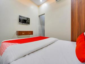 a bedroom with a white bed with a red blanket at Hotel O R.S in Nagpur +49 photos