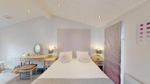 a white bedroom with a bed and a desk at Unity Beach in Berrow +128 photos