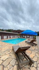 two picnic tables with an umbrella next to a swimming pool at Hotel Beira Rio Guararema in Guararema