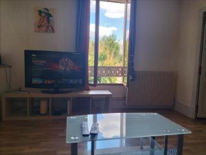 a living room with a glass table and a tv at l'oasis de paix in Dijon
